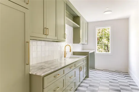 a kitchen with granite countertop a sink and a white wooden cabinets