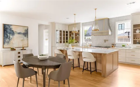 a kitchen with a dining table chairs and white cabinets