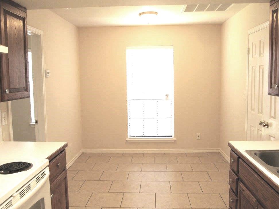 8811 Clearbrook Trail Austin, TX 78729 - Photo 7 of 38 lft A - A well-lit kitchen area features a bright window and durable tile flooring.