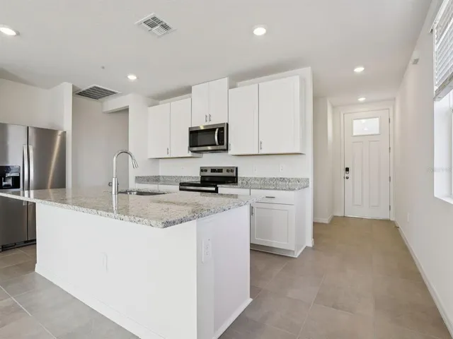 a large kitchen with stainless steel appliances granite countertop a stove a sink a refrigerator and a granite counter tops with a window