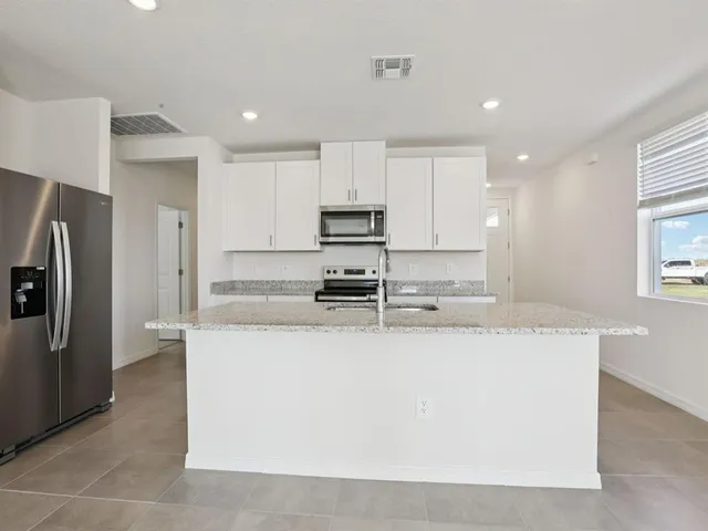 a kitchen with granite countertop a sink and white cabinets