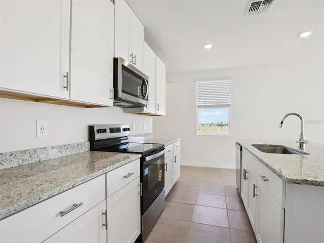 a kitchen with stainless steel appliances granite countertop a sink a stove a microwave and a refrigerator