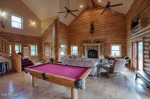 a living room with furniture pool table wooden floor and a fireplace