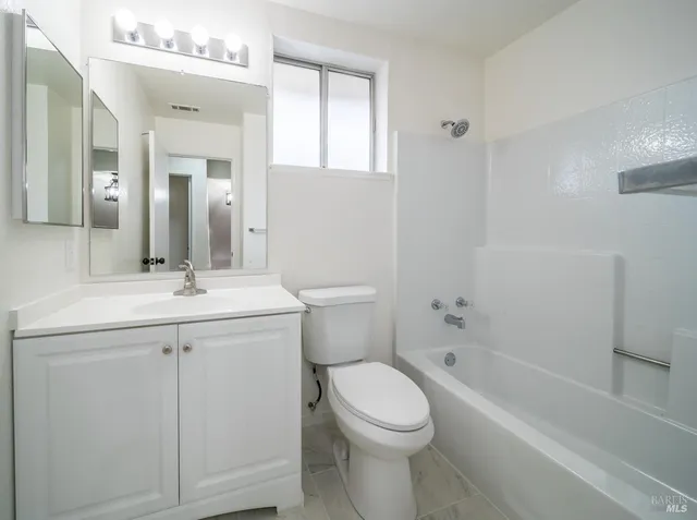 a bathroom with a granite countertop sink a toilet and shower