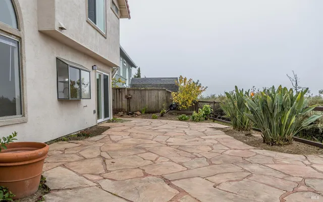 a view of a house with potted plants and a bench