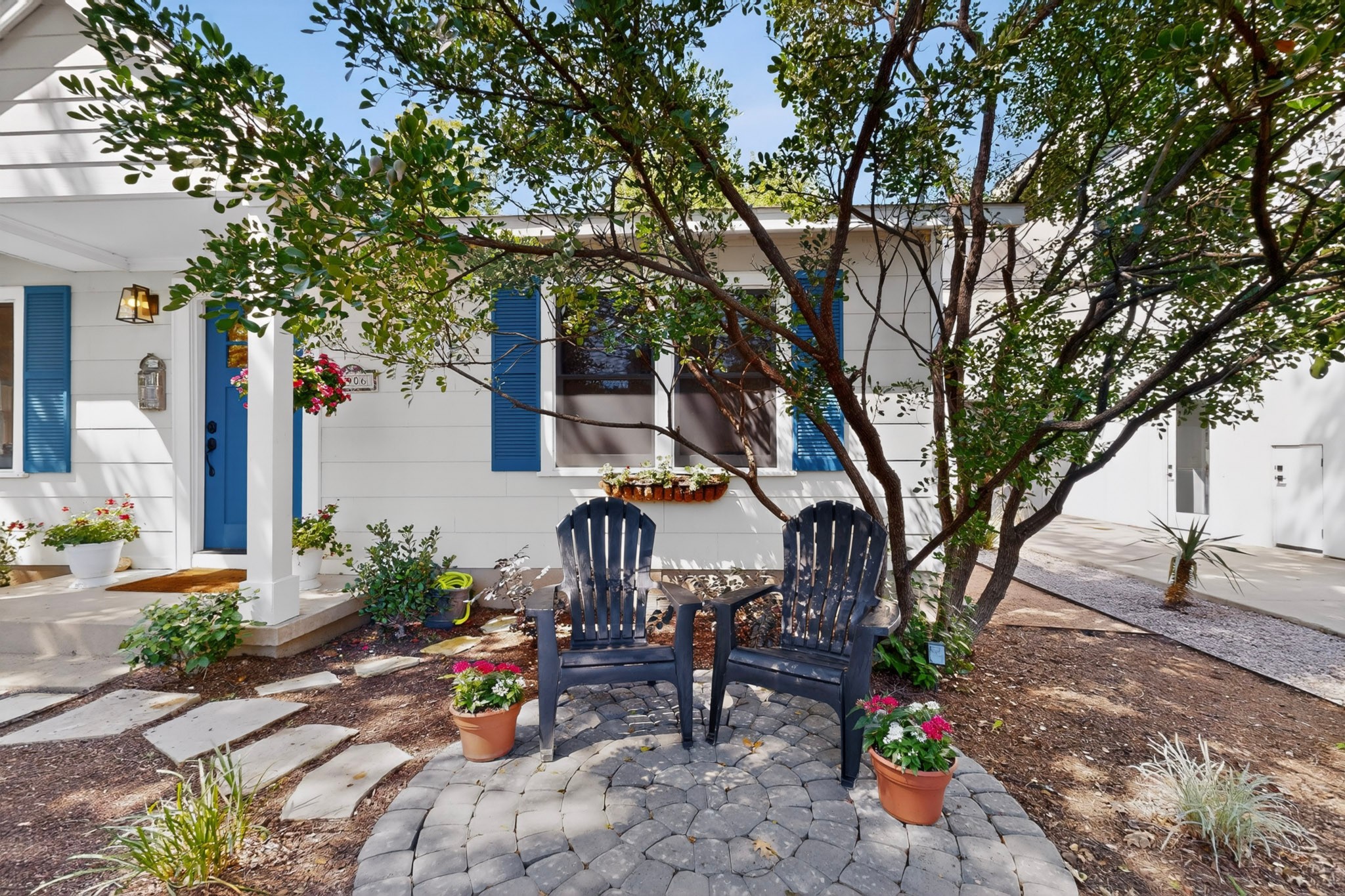 1906 Collier Street Austin, TX 78704 - Photo 2 of 40 A light yellow exterior with vibrant blue shutters, inviting entry, with a blue front door and a cozy patio.