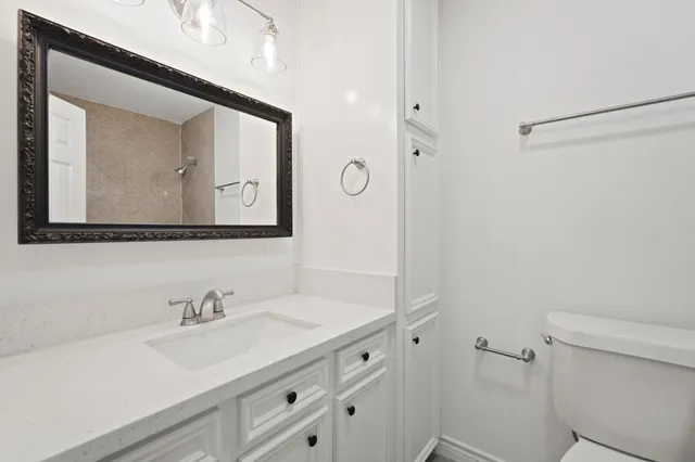 a bathroom with a toilet sink vanity and mirror