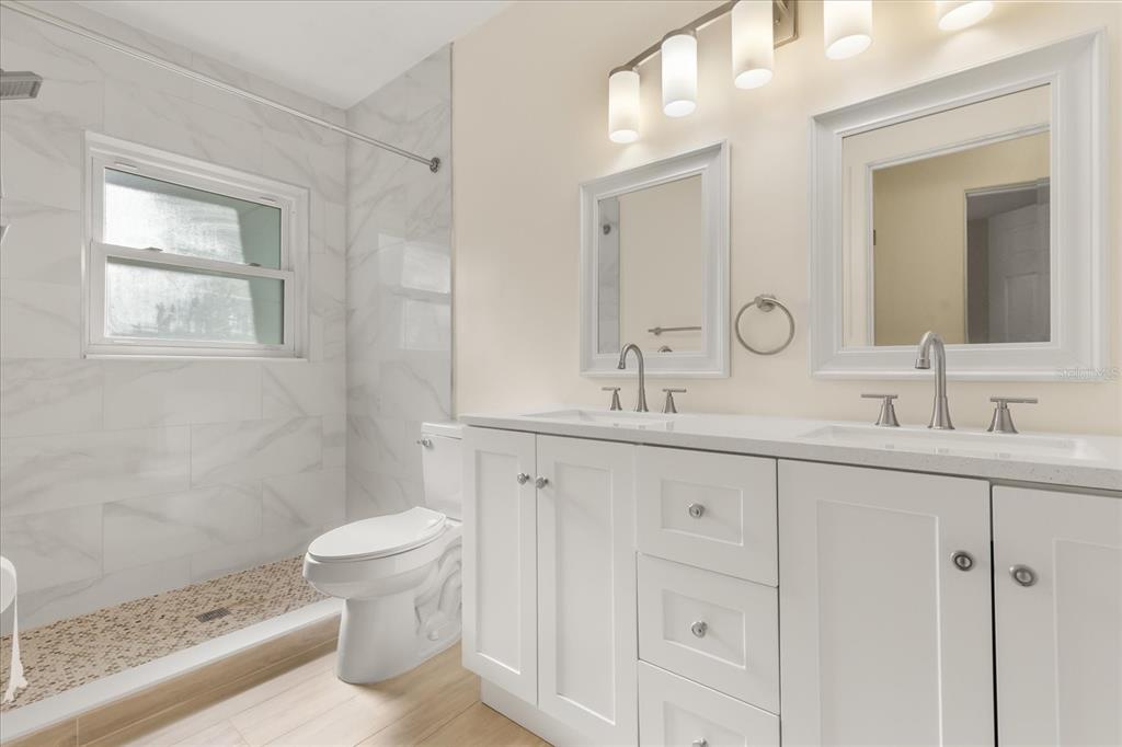 12432 136th Lane Largo, FL 33774 - Photo 15 of 24 a bathroom with double vanity sink a mirror and a toilet