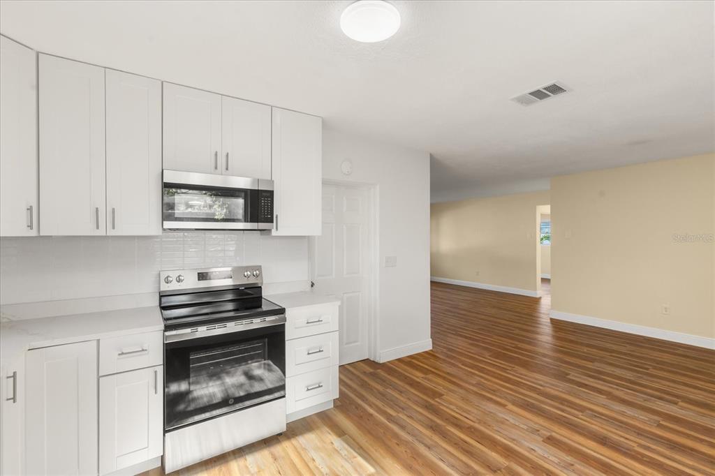12432 136th Lane Largo, FL 33774 - Photo 9 of 24 a kitchen with wooden floor a stove and a refrigerator