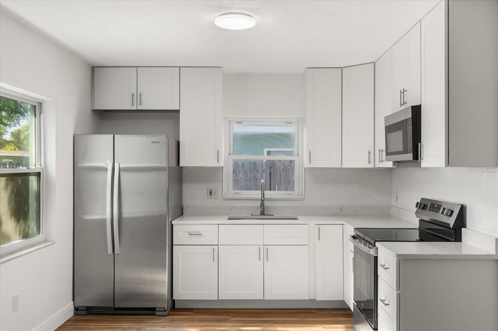 12432 136th Lane Largo, FL 33774 - Photo 10 of 24 a kitchen with stainless steel appliances granite countertop a refrigerator sink and white cabinets