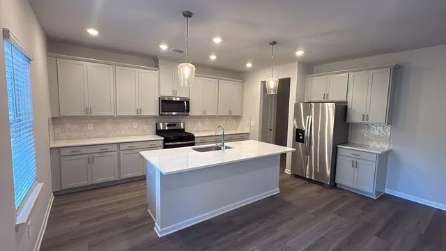 a kitchen with kitchen island a sink stainless steel appliances and refrigerator