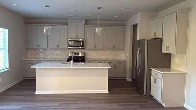 a kitchen with stainless steel appliances granite countertop a sink a stove a refrigerator and island with wooden floor