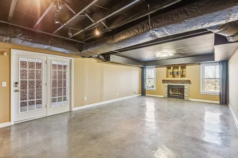 a view of an empty room with a fireplace and a ceiling fan