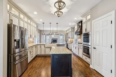 a kitchen with stainless steel appliances granite countertop a refrigerator a stove oven and white cabinets