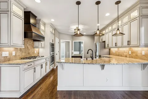 a large kitchen with stainless steel appliances granite countertop a sink a stove and a wooden floors