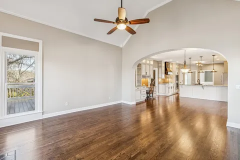a view of an empty room with window wooden floor and a ceiling fan