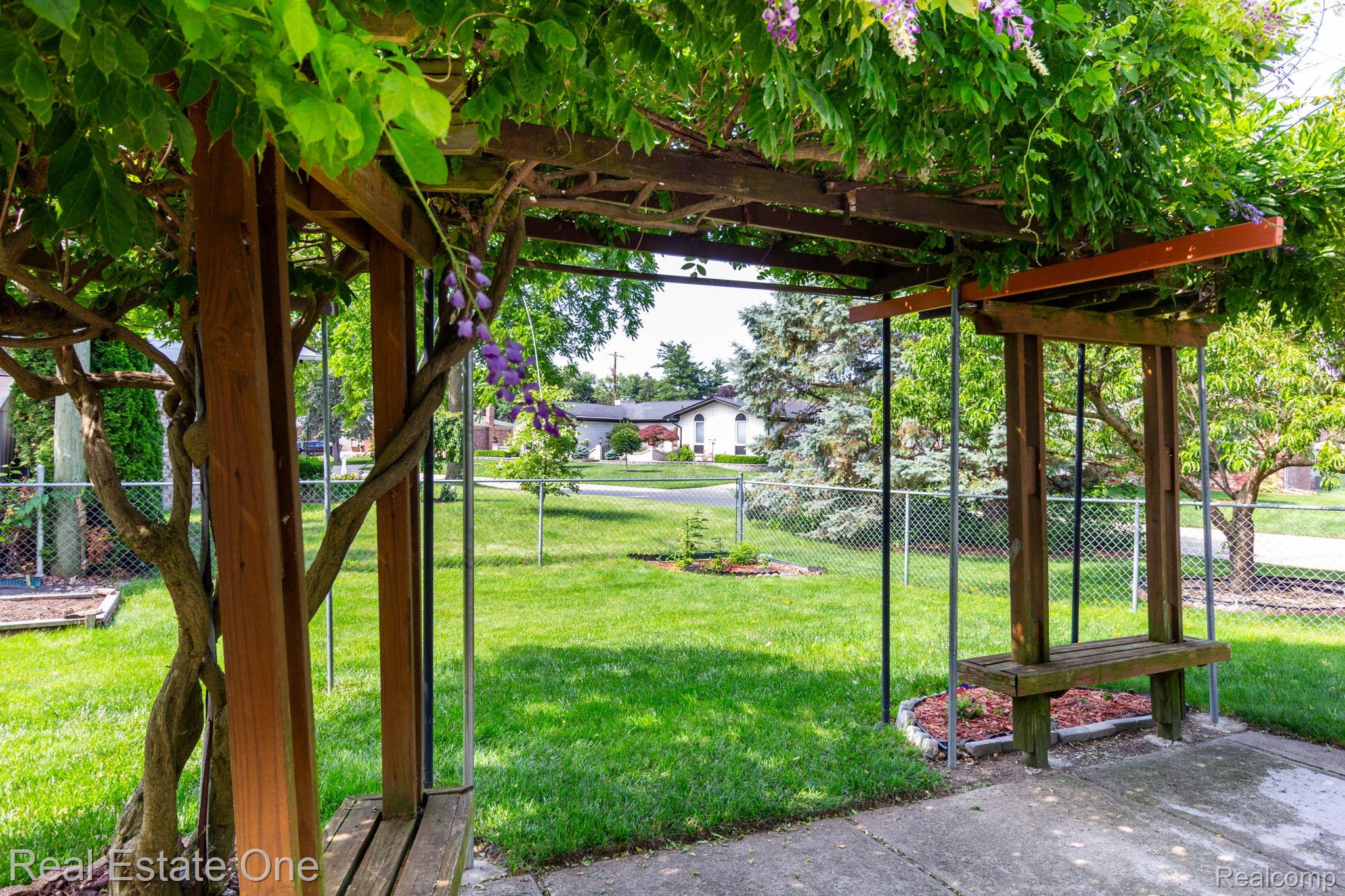 13912 Clinton River Road Sterling Heights, MI 48313 - Photo 34 of 43 Covered patio area featuring a wooden pergola with climbing foliage, integrated wooden swing seats, and a concrete patio surface