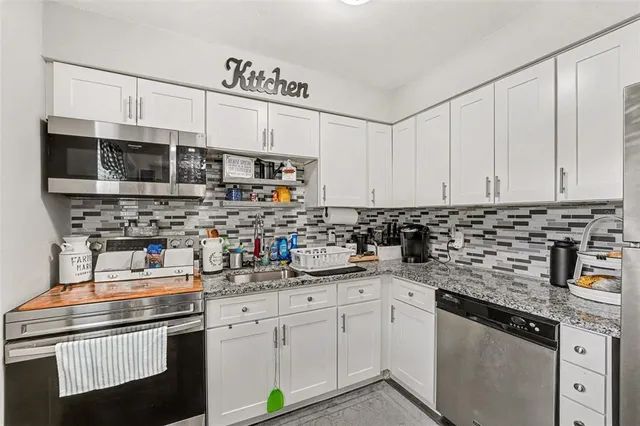 a kitchen with stainless steel appliances granite countertop a sink a stove a microwave a counter space and cabinets