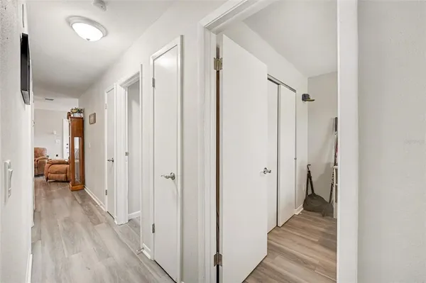 a view of a hallway with wooden floor and a bathroom