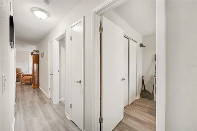a view of a hallway with wooden floor and a bathroom