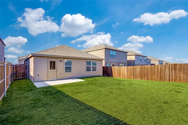 a view of a yard in front of a house with plants and large tree