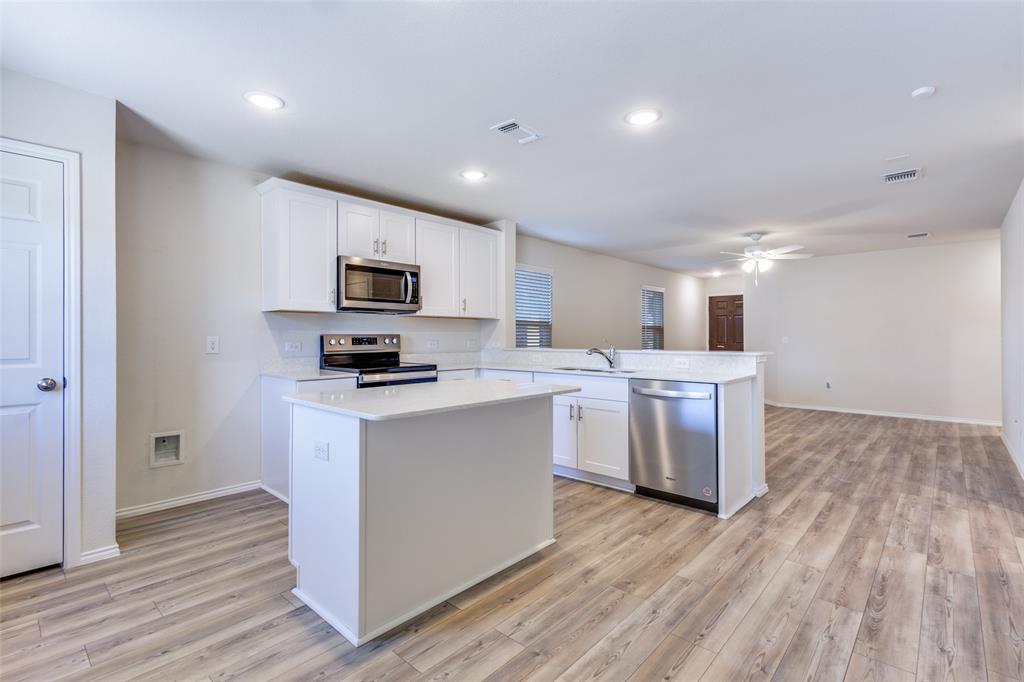 843 Ozark Path Princeton, TX 75407 - Photo 5 of 13 a kitchen with stainless steel appliances a stove top oven a sink a refrigerator white cabinets and wooden floor