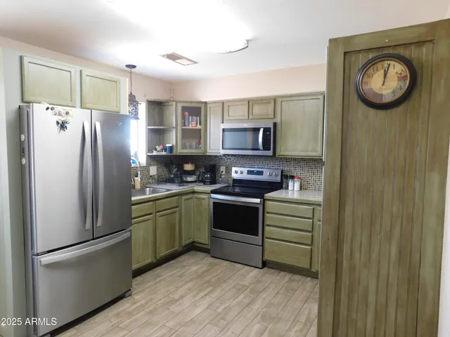 a kitchen with stainless steel appliances granite countertop a refrigerator a stove and a wooden floors
