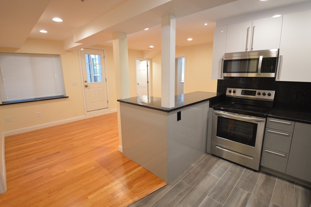 1801 Beacon Street, Unit 2 Brookline, MA 02445 - Photo 2 of 14 a kitchen with stainless steel appliances kitchen island granite countertop a stove a sink and a microwave