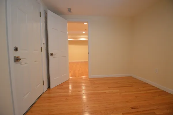 a view of an empty room with wooden floor and a shower