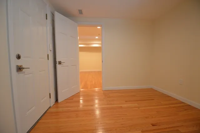 a view of an empty room with wooden floor and a shower