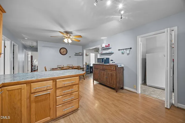 a open kitchen with cabinets a stove and a ceiling fan