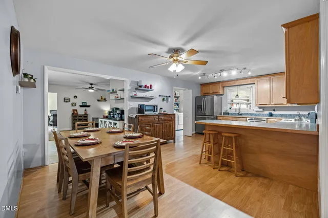 a view of a dining room and livingroom with furniture wooden floor a rug a painting and a chandelier