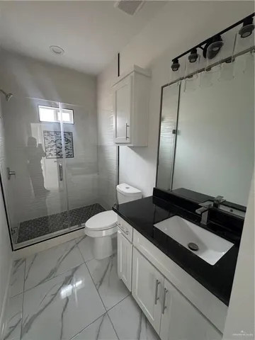 a bathroom with a granite countertop sink toilet and shower