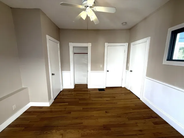 a view of empty room with window and wooden floor