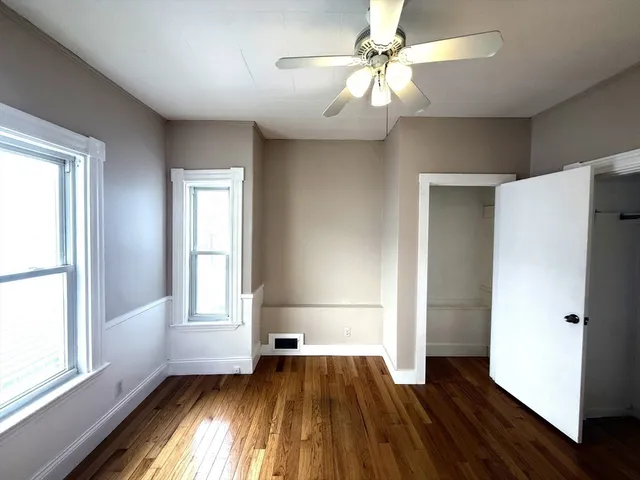 a view of empty room with wooden floor and fan