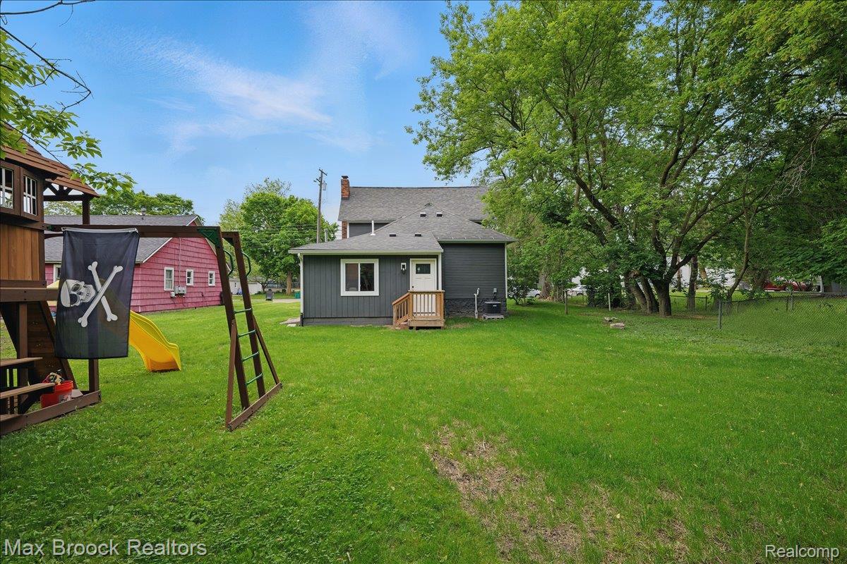 515 East Clinton Street Howell, MI 48843 - Photo 25 of 29 Rear view of house with a playground, a chimney, a yard, and roof with shingles