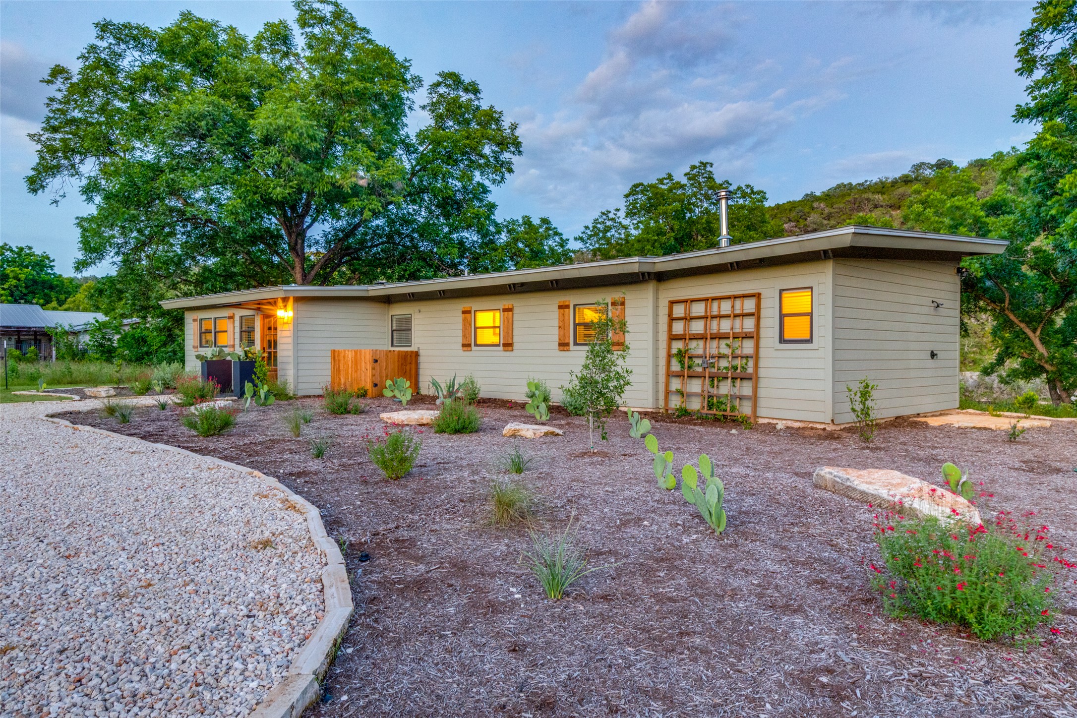 303 Lago Verde Road Austin, TX 78734 - Photo 3 of 39 Modern desert landscaping surrounds this sleekly designed home, offering an inviting blend of natural beauty and contemporary architecture.