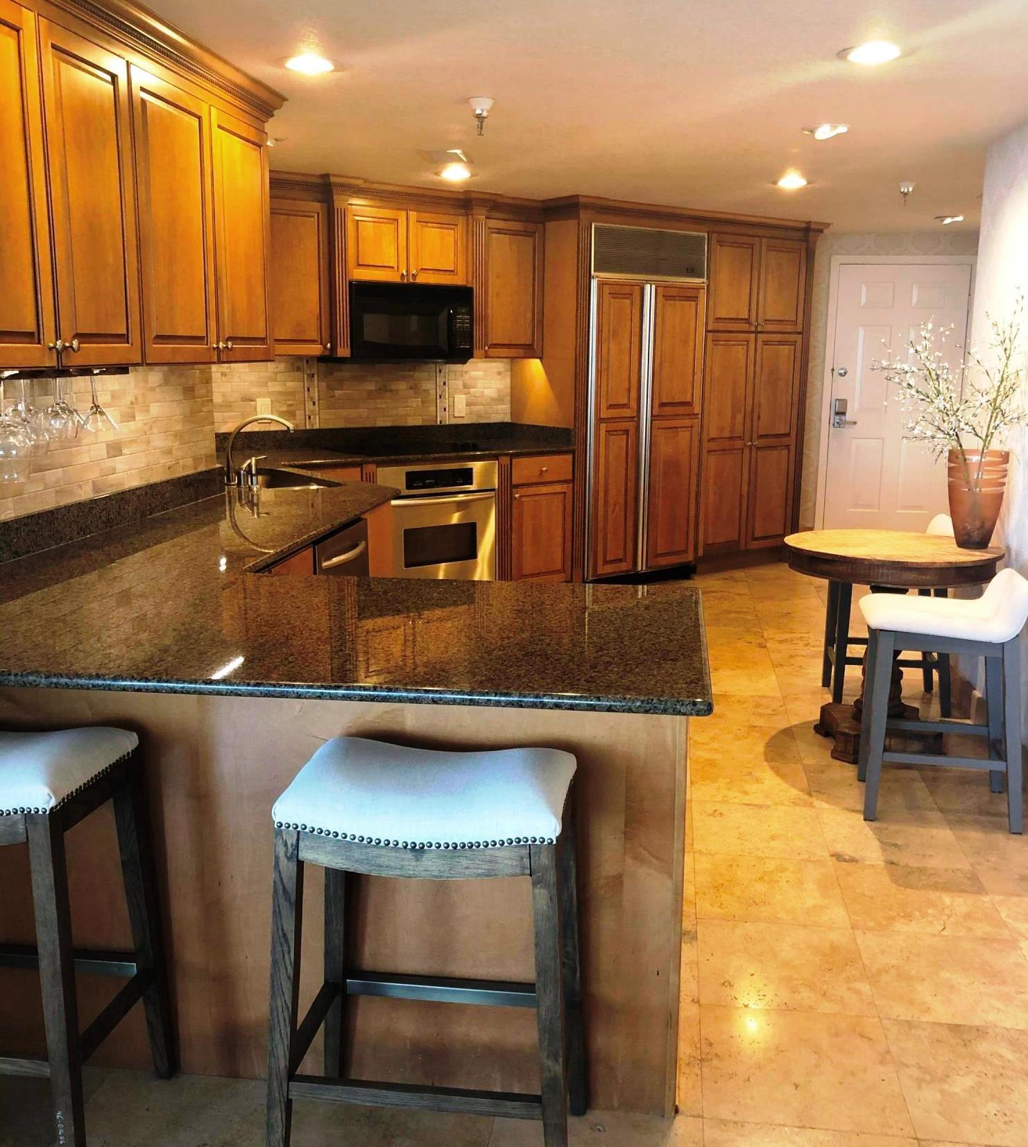 320 Harbor Boulevard, Unit 502 Destin, FL 32541 - Photo 11 of 22 a kitchen with stainless steel appliances granite countertop a stove top oven a sink a dining table and chairs with wooden floor