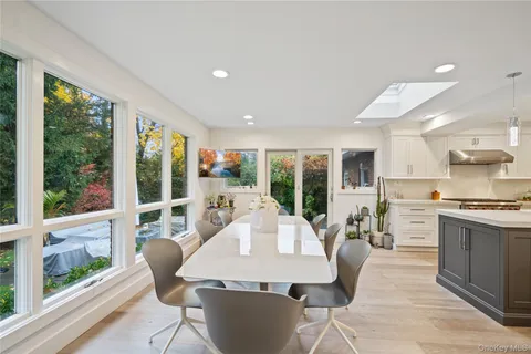 a living room with stainless steel appliances granite countertop furniture a large window and a kitchen view