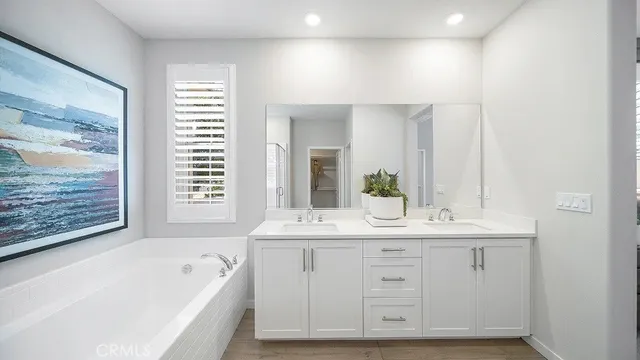 a spacious bathroom with a double vanity sink a mirror and a bathtub