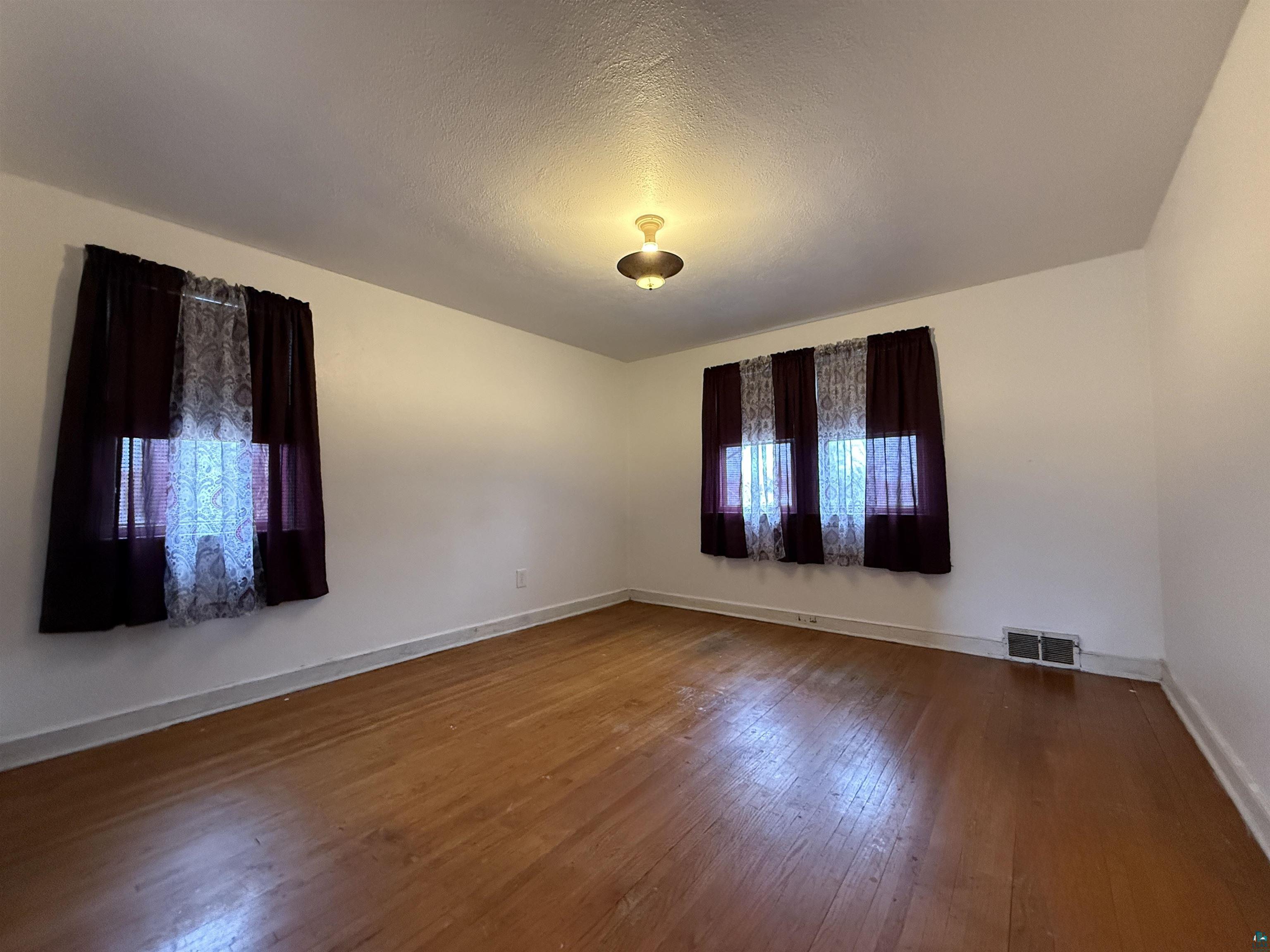 3001 3rd Avenue West Hibbing, MN 55746 - Photo 26 of 38 Unfurnished room featuring dark wood finished floors and a textured ceiling