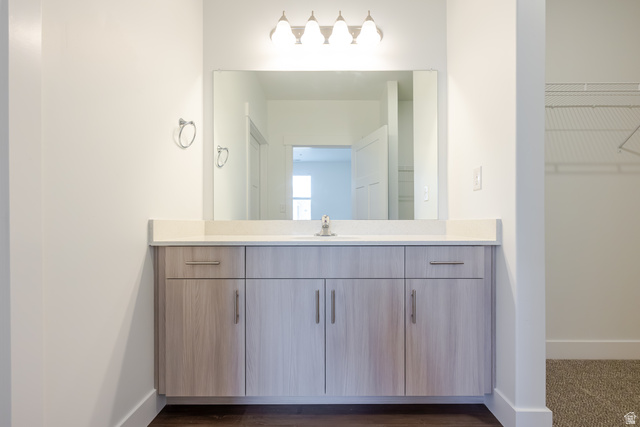 4695 South 690th West, Unit U101 Mapleton, UT 84664 - Photo 9 of 16 Bathroom vanity featuring a single basin, light-toned wood-finish cabinetry, a white countertop, and a large mirror with overhead lighting