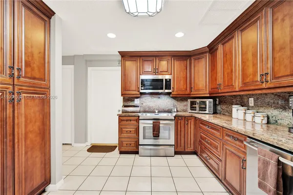 a kitchen with stainless steel appliances granite countertop a refrigerator and a stove top oven