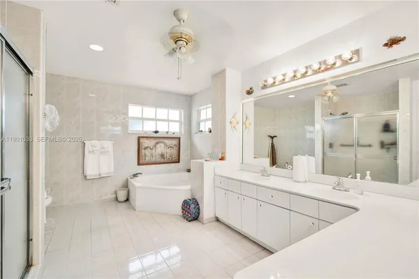 a large white bathroom with a double vanity sink mirror and shower