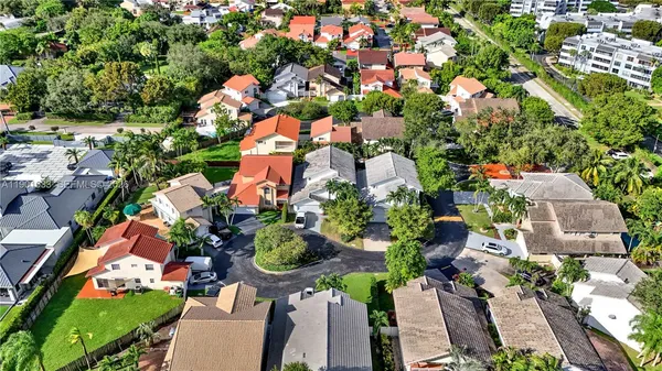 an aerial view of residential houses with outdoor space and trees all around