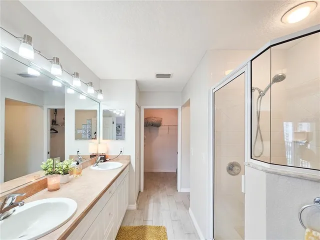 a bathroom with double vanity sink a mirror a toilet and a shower