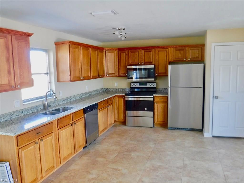 a kitchen with stainless steel appliances granite countertop a refrigerator stove top oven a sink and dishwasher