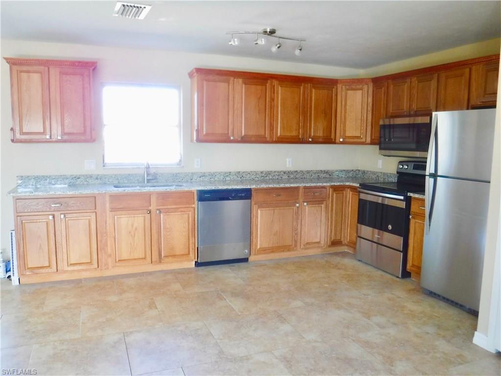 106 Oleander Road Lehigh Acres, FL 33936 - Photo 2 of 17 a kitchen with stainless steel appliances granite countertop a stove top oven a sink and dishwasher