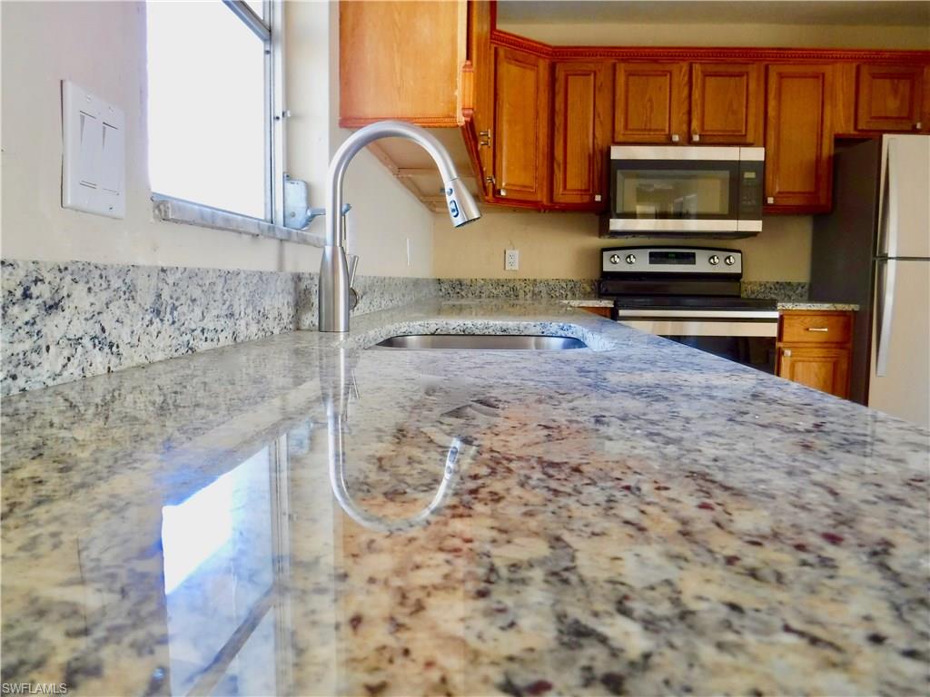 106 Oleander Road Lehigh Acres, FL 33936 - Photo 4 of 17 a kitchen with stainless steel appliances granite countertop a stove a sink and a microwave