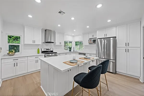 a kitchen with a refrigerator a stove a sink dishwasher with a dining table and chairs